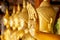 Hand of golden Buddha statue with a gold leaf on blurred golden Buddha statue stand strong line background