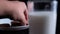 Hand grabbing cookie from a plate behind a glass of milk