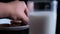 Hand grabbing cookie from a plate behind a glass of milk