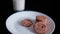 Hand grabbing cookie from a plate next to a glass of milk