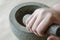 Hand grinds the dried roots of medicinal herbs in stone mortar