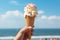 A hand grips an ice cream cone beneath the azure sky