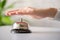 Hand of guest ringing in silver bell. reception desk with copy space. Hotel service. Selective focus.