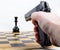 Hand with gun took aim at chess piece
