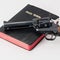 Hand gun on the top of an old Bible with red pages
