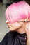 Hand of a hairdresser cutting short pink with scissor hair in a hairdressing salon, close up, side view.