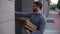 Hand held shot of delivery man coming to door and rings doorbell. Courier holding boxes with pizza.