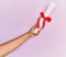 Hand of hispanic man holding graduated diploma over isolated pink background