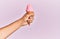 Hand of hispanic man holding ice cream over isolated pink background