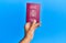 Hand of hispanic man holding spanish passport over  blue background