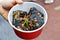 A Hand Hoiding A Box with Black Deep Fried Stinky Tofu.