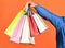 Hand hold bags. Shopping bags in hand on red background. Paper bags different colors. Shopping in mall. Black friday