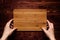 Hand hold blank bamboo sign board on brown vintage wood plank, top view.