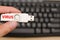 Hand hold blank USB virus thumb drive or virus USB stick with keyboard in the background