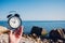 Hand hold watch on beach background.Alarm clock on sea and sand background different time with summer vacation.Vacation time conce