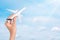 Hand holding airplane over blue sky background. Flight, travel concept