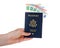 Hand holding American passport with Euro bills sticking out isolated