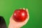 A hand holding an apple in green screen studio