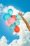 Hand holding balloons sky background