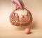 Hand holding basket with farm eggs. Easter celebration tradition or organic food concept on beige background