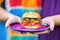 hand holding bbq slider over a colorful plate