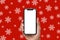Hand holding the black smartphone with a blank screen and modern frameless design on Christmas background of snowflakes