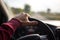 Hand holding on black steering wheel while driving in the car