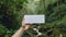 hand holding blank white card against rainforest background