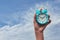 hand holding a blue Alarm clock against white background