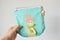 Hand holding blue handmade zipper pouch with cute doll