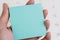 Hand holding blue sticky note or adhesive paper with copy space for writing message on white clean calendar using as reminder for