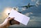 Hand holding boarding pass and passport book with plane flying background