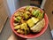 Hand holding bowl of Chinese cucumber and dumplings with hot chilis