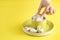 Hand holding bowl of sweet Marshmallow pastel isolated on yellow