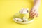 Hand holding bowl of sweet Marshmallow pastel isolated on yellow