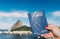 Hand holding Brazilian passport with SugarLoaf Mountain in Rio de Janeiro, Brazil in background