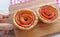 Hand Holding a Breadboard of Two Mini Apple Rose Shaped Tartlets