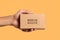 A hand holding a brow mailing box mockup, in the style of melting, light brown Generative AI