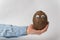 Hand holding brown coconut with Googly eyes and funny face. White background
