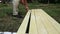 Hand holding a brush applying varnish paint on a wooden surface. Painting woodwork outside.