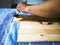 Hand holding brush shows how to apply stain to wood planks.