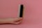 Hand holding brush with stone scrub foot hygiene tool on pink background