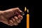 Hand holding burning gas lighter to light candle. Studio shot is