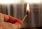 Hand holding a burning match. Match with fire and flame on a dark background. The concept of arson and fire. A burning match in hi