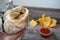 A hand holding a California-style burrito wrapped in foil above a wood table