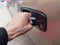 Hand holding a car door handle, opening the door. Car theft prevention simple concept