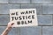 Hand holding cardboard banner with text We Want Justice, hashtag BLM, Black Lives Matter. Anti-racism protest