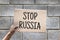 Hand holding cardboard with text STOP RUSSIA. Anti-war protest. RUSSIAN WAR. Aggressive invasion