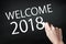 Hand holding a chalk and writing welcome 2018