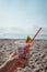 Hand holding cocktail with garbage on background of clean beach, ocean waves. Plastic ocean pollution, environmental crisis. Say